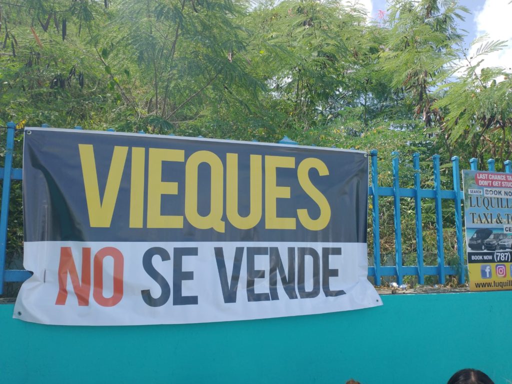 VIEQUES IS NOT FOR SALE.  On August 12th 2022 we returned to put up the banner in the place where it has been taken down by the municipality. Notice that there is a commercial sign next to our banner which the Municipality did not take down. 
ESPAÑOL 
On August 12th 2022 we returned to put up the banner in the place where it has been taken down by the municipality. Notice that there is a commercial sign next to our banner which the Municipality did not take down.  Spanish: el 12 de agosto de 2022 volvimos a colocar la pancarta en el lugar donde la ha retirado el municipio. Nótese que hay un cartel comercial al lado de nuestra pancarta que la Municipalidad no quitó.